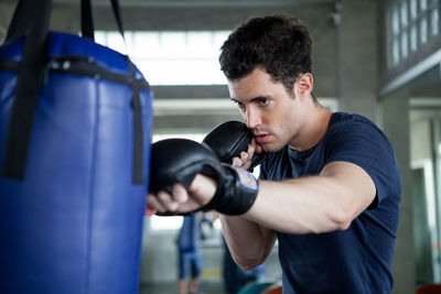 Young man boxing using punching bag in gym