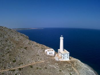 Lighthouse by sea against sky