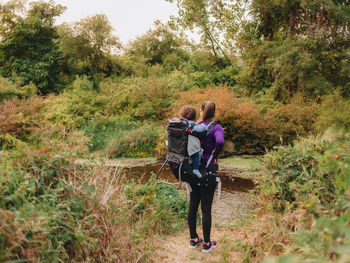 Smiling mother with cute son on back standing on forest