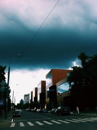Cars on road against cloudy sky