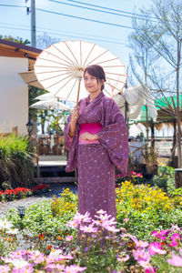 Woman with umbrella standing against plants