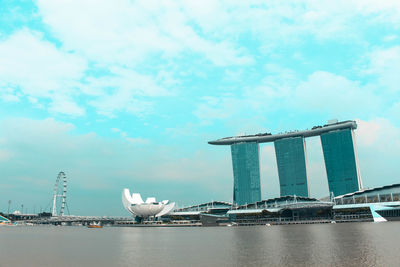 Sea by modern buildings against sky in city