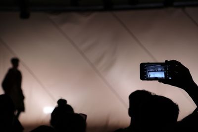 Silhouette man photographing with mobile phone during concert