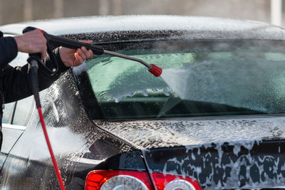 Cropped image of man washing car at garage