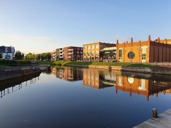 Reflection of buildings in river against clear sky