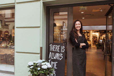 Portrait of smiling saleswoman standing at doorway in boutique