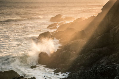 Waves breaking against sea during sunset