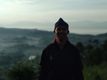 Portrait of smiling man standing against mountain