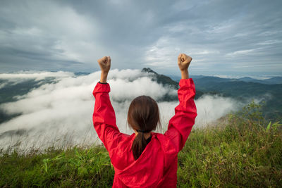 Rear view of woman with arms raised against sky