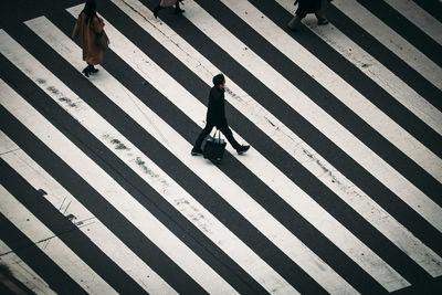 Shadow of woman walking on zebra crossing