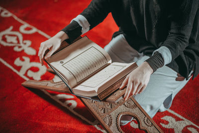 Midsection of woman with koran at mosque