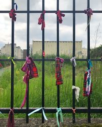 Clothes hanging on fence by field against sky