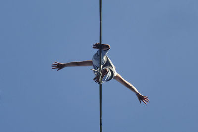 Low angle view of woman standing cable against clear sky