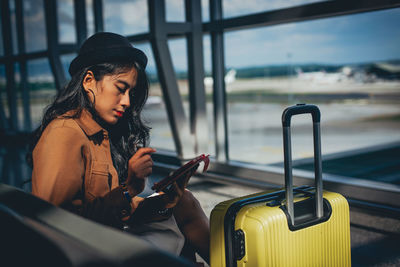 Woman using mobile phone at airport departure area