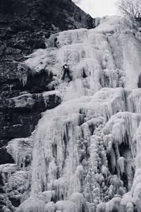 Icicles on rocks against clear sky during winter