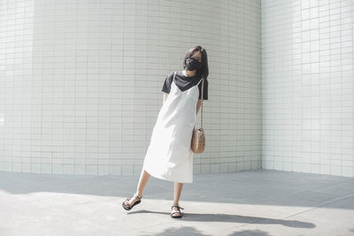 Woman with umbrella standing against wall