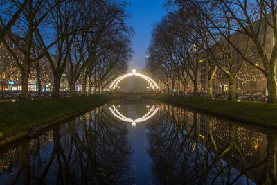 Reflection of trees in water against clear sky