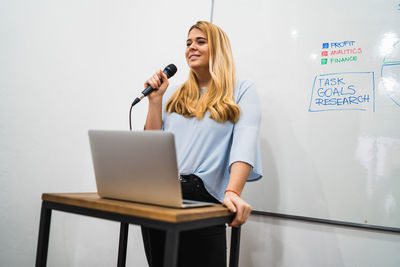 Businesswoman giving presentation using microphone in conference room