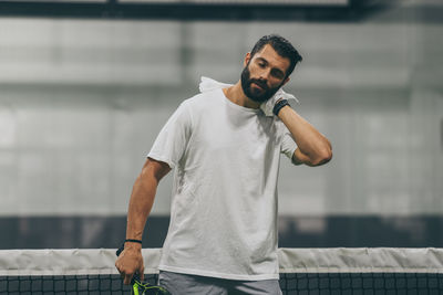 Beautiful man playing paddle tennis, racket in hand wipes the sweat. young sporty boy after match. 