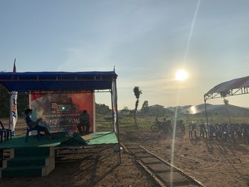 People at railroad station against sky during sunset