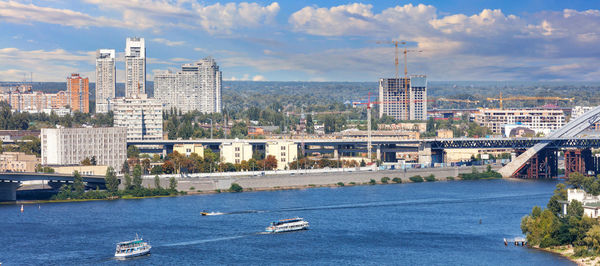 City panoramic landscape of kyiv with the dnipro river in the foreground, boats ply.