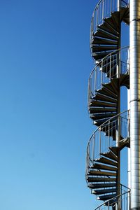 Low angle view of fire escape against clear blue sky