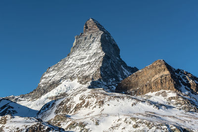 Low angle view of snowcapped mountains against clear sky