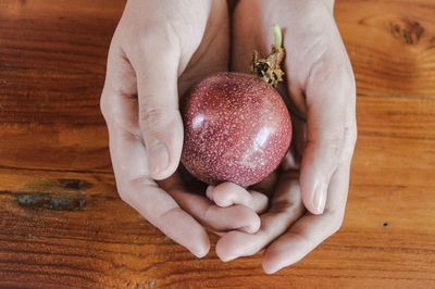 Close-up of hand holding a passion fruit