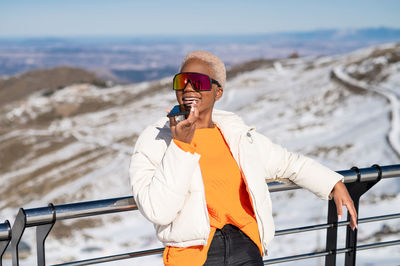 A young african american woman wearing sunglasses having fun in the snow on a winter day