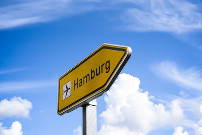 Low angle view of road sign against blue sky