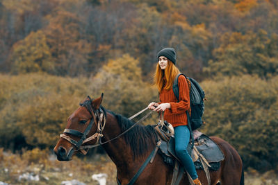Young woman riding horse in autumn