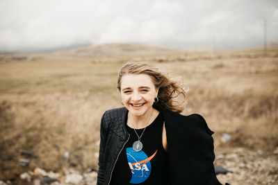 Portrait of smiling young woman standing on field