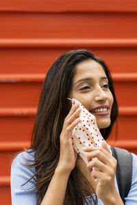 Portrait of a smiling young woman holding red outdoors