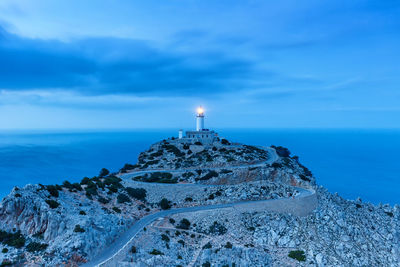 Lighthouse by sea against blue sky