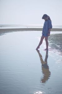 Full length of woman standing on beach against sky