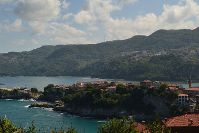 Town by sea and mountains against sky