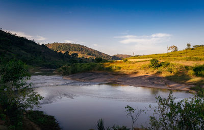 Scenic view of river by mountains against sky