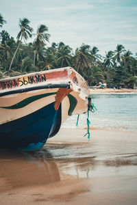 Boat moored on beach against sky