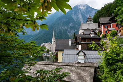 House amidst trees and buildings against mountains