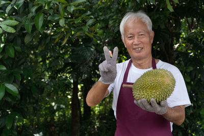 Man with arms raised standing against plants