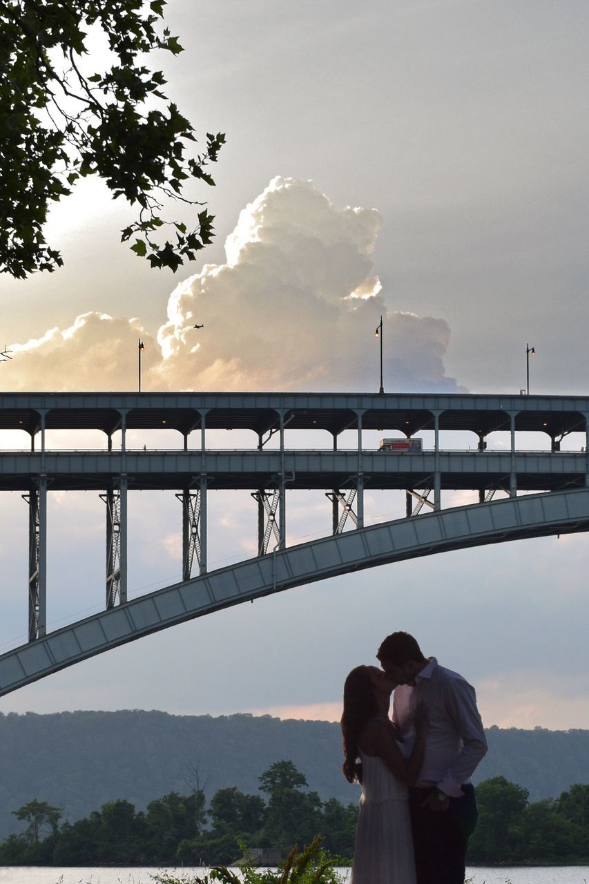 two people, sky, real people, men, connection, togetherness, bridge - man made structure, women, love, architecture, cloud - sky, railing, built structure, couple - relationship, water, lifestyles, tree, outdoors, nature, bonding, day, standing