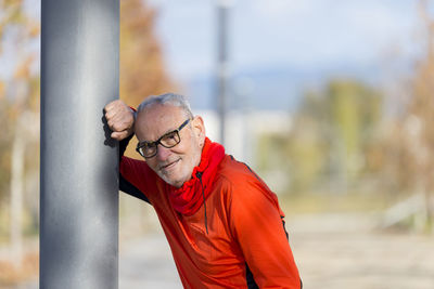 Portrait of senior man leaning on pole