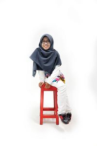 Portrait of young woman sitting against white background