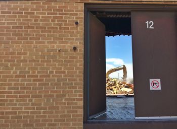 Excavator at construction site seen through open door