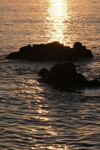 Scenic view of rocks in sea during sunset