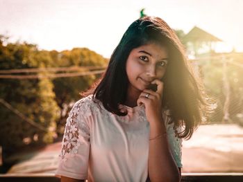 Portrait of beautiful young woman standing against sky