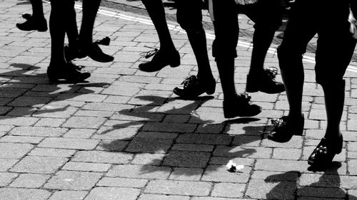 Low section of people walking on cobblestone ground