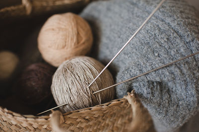 Making homemade knitted sweater at home. straw basket with yarn wool skein with knitted fabric