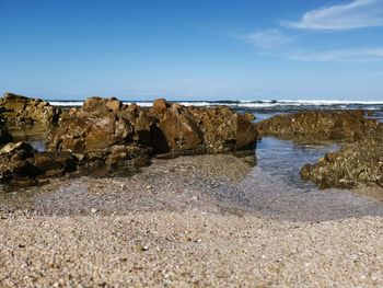 Rocks on beach against blue sky