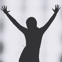 Silhouette person with arms raised standing against white background